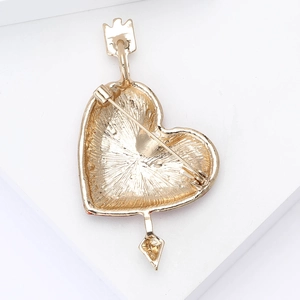 Macro view of the golden alloy heart brooch back with a needle and arrow design detail