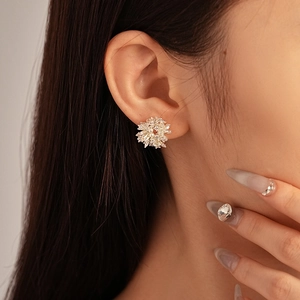 Primo piano di un orecchino a fiore con zirconi e perle sull'orecchio della modella