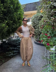 Three-piece women's set with khaki lantern pants and cropped top in garden setting