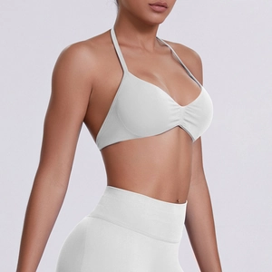 Detail of white halter neck sports bra with ruched center and high-waist leggings