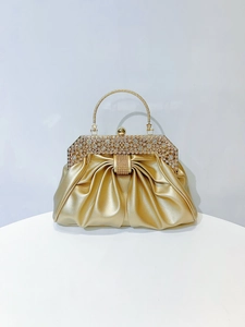 Detail of the sparkling rhinestones on the gold pleated evening bag metal handle
