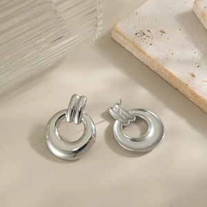 Close-up of geometric interlocking silver hoop earrings on a minimalist background