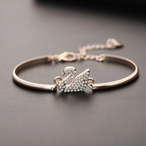 Macro view of rose gold swan bangle with clear crystals and adjustable chain