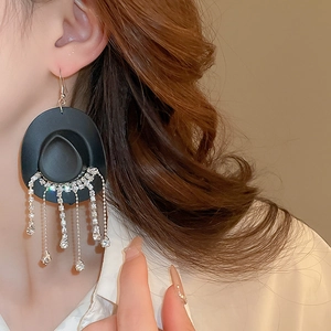 Close-up of model wearing black cowboy hat earrings with long crystal tassel fringe