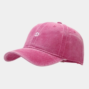 Detailed view of white letter D embroidery on pink washed denim baseball cap texture