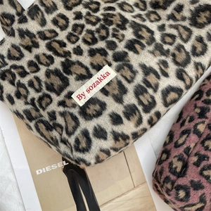 Close-up of leopard print tote bags in thick wool fabric with woven brand label detail
