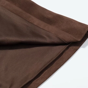 Gros plan sur la texture en daim marron foncé avec couture d'ourlet et fini doux