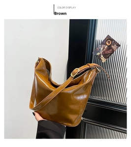 Detail shot of caramel brown oil wax leather tote bag showing glossy pleated texture
