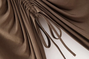 Detailed close-up of brown ruched fabric with adjustable drawstring and silky texture
