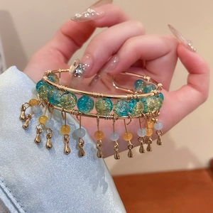 Vue macro détaillée du bracelet doré avec des perles de verre turquoise et des glands en métal
