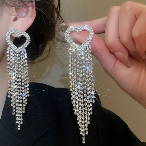 Macro detail of heart-shaped zircon earrings with long sparkling tassel fringes on model