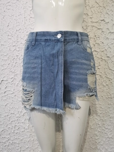 Detalle de falda pantalón vaquera azul claro con rotos desgastados y bordes deshilachados
