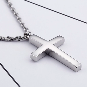 Gros plan du pendentif croix en argent poli avec une chaîne torsadée en métal élégant