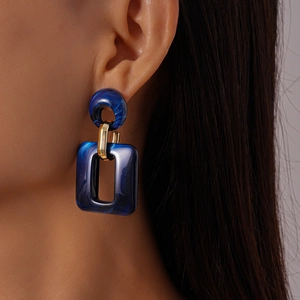 Blue marble resin drop earring with gold metal link shown on model in close-up detail
