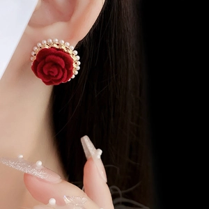 Gros plan de boucles d'oreilles roses rouges avec perles portées pour un look élégant