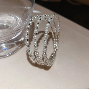 Detailed close-up of triple-layer pearl bracelet with sparkling rhinestone accents