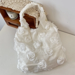Detail of white canvas tote bag featuring layered 3D organza flower textures and a soft aesthetic