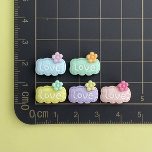 Detailed view of colorful 2cm resin cloud charms with Love text on a measuring mat