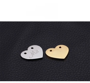 Detailed view of polished heart-shaped pendants with Mae engraving in gold and silver