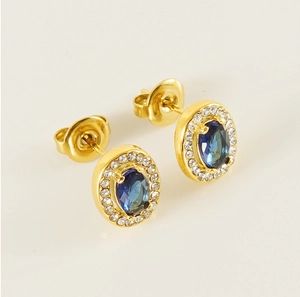 Macro shot of gold-plated oval earrings with blue zircon center and butterfly backs