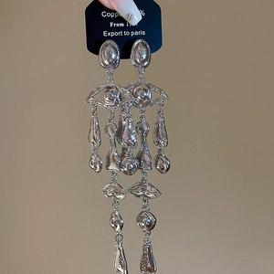 Detail of silver long drop earrings with surrealist eye and lip motifs and metal charms