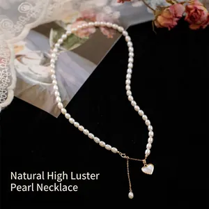 Natural freshwater pearl necklace with gold heart shell pendant on black velvet background