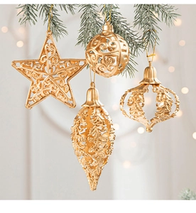 Detail of four golden baroque ornaments hanging on snow-covered Christmas pine branches