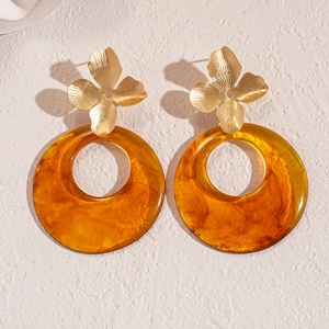 Resin hollow round flower earrings with gold petals and amber rings on a beige background
