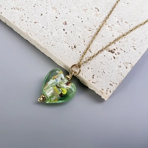 Close-up of green glass heart pendant necklace with gold foil accents on stone