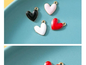 Macro shot of colorful enamel heart charms in black, pink, white, and red with gold loops