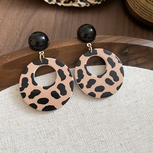 Detailed close-up of retro leopard print hoop earrings with black spherical studs