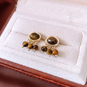 Macro shot of vintage gold earrings with oval brown stone and hanging beads in a gift box