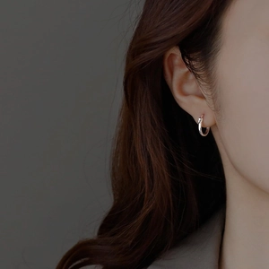 Macro side view of a small minimalist S925 sterling silver hoop earring worn on the ear