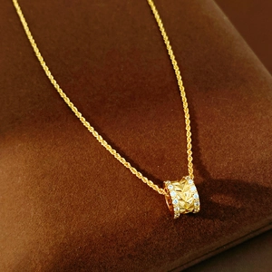 Detail of 18k gold plated necklace featuring a textured cylinder pendant with zircons