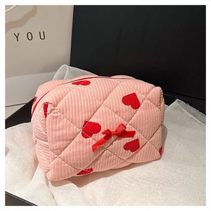 Detail of pink corduroy makeup bag with red heart pattern and cute bow decoration