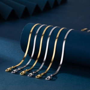 Macro shot of gold and silver flat snake chains with lobster clasps on blue display