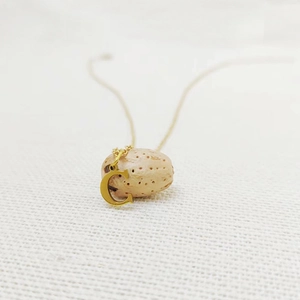 Detailed view of a gold-plated letter C pendant on a fine chain over a natural texture