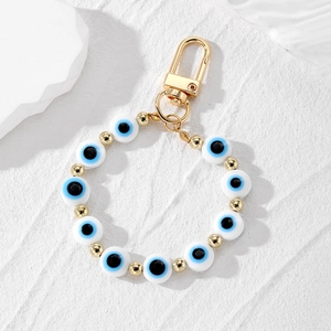 Macro shot of evil eye beads with golden lobster clasp and beads on a stone surface