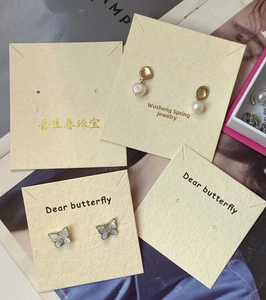 Detailed shot of pearl and butterfly earrings fixed on a square jewelry display card