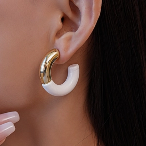 Close-up of a model wearing a gold and white acrylic C-shaped hoop earring
