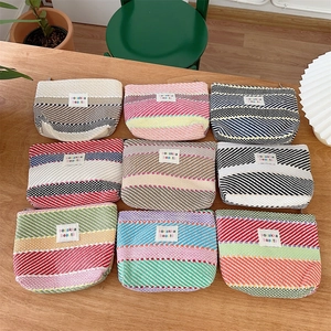 Top-down view of nine large capacity colorful striped woven cosmetic and toiletry bags