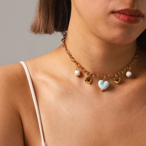 Gold chain necklace with blue marble heart and floral beads on model neck