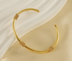 Detail of 18K gold-plated stainless steel cuff bracelet with triple chain-wrap textures