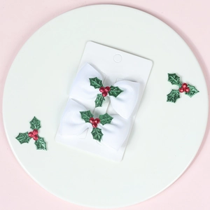 Detail of white grosgrain ribbon bows with holly berry sequins on display card
