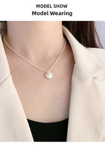 Close-up of S925 sterling silver chain and baroque pearl worn by model on neckline