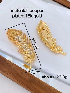 Macro view of 18K gold plated copper feather brooch with zircon stones measuring 81.7x26mm