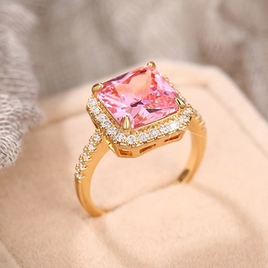 Close-up of a luxury gold ring with a square pink gemstone and pavé crystal details