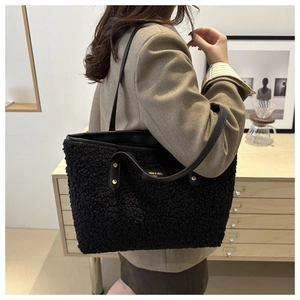 Close-up of black faux fur tote bag featuring smooth leather trim and gold rivet details