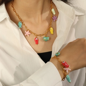 Golden chain jewelry set with colorful fish and starfish charms on a white shirt