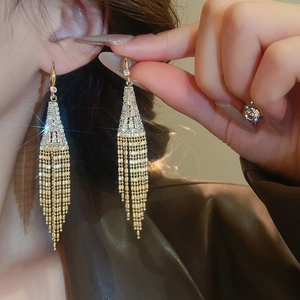 Macro view of long gold tassel earrings with white zircon on a model for a luxury look